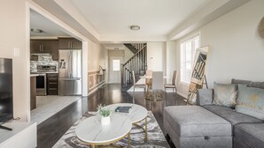 Una sala moderna con un sofá gris, una mesa de centro y un comedor con una silla y una mesa.