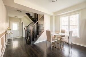 A dining area with a round table, four chairs, and a staircase with wooden railings.