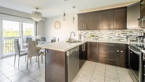 Una cocina moderna con armarios oscuros, una isla grande y un comedor con sillas y una mesa.