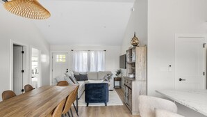 Un salon moderne avec une table à manger en bois, un canapé et un téléviseur.