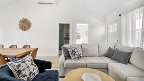 Un salon moderne avec un canapé, une table basse ronde et une table à manger avec des chaises.