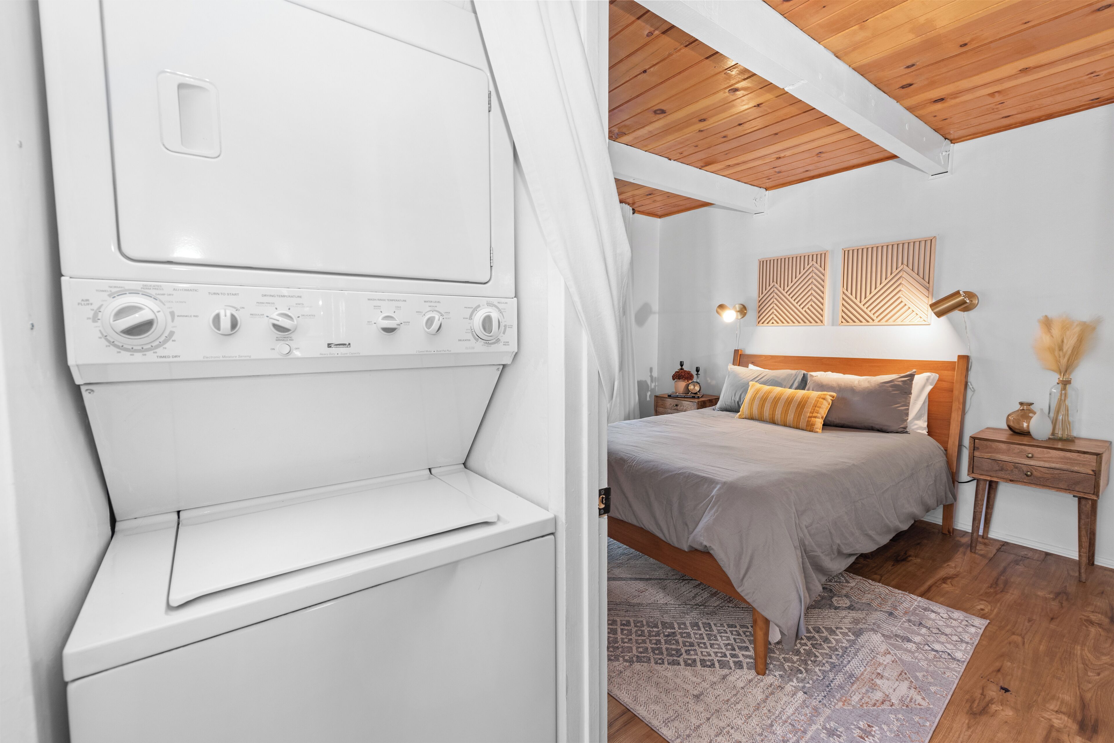 Un dormitorio con cama, mesitas de noche y techo de madera.