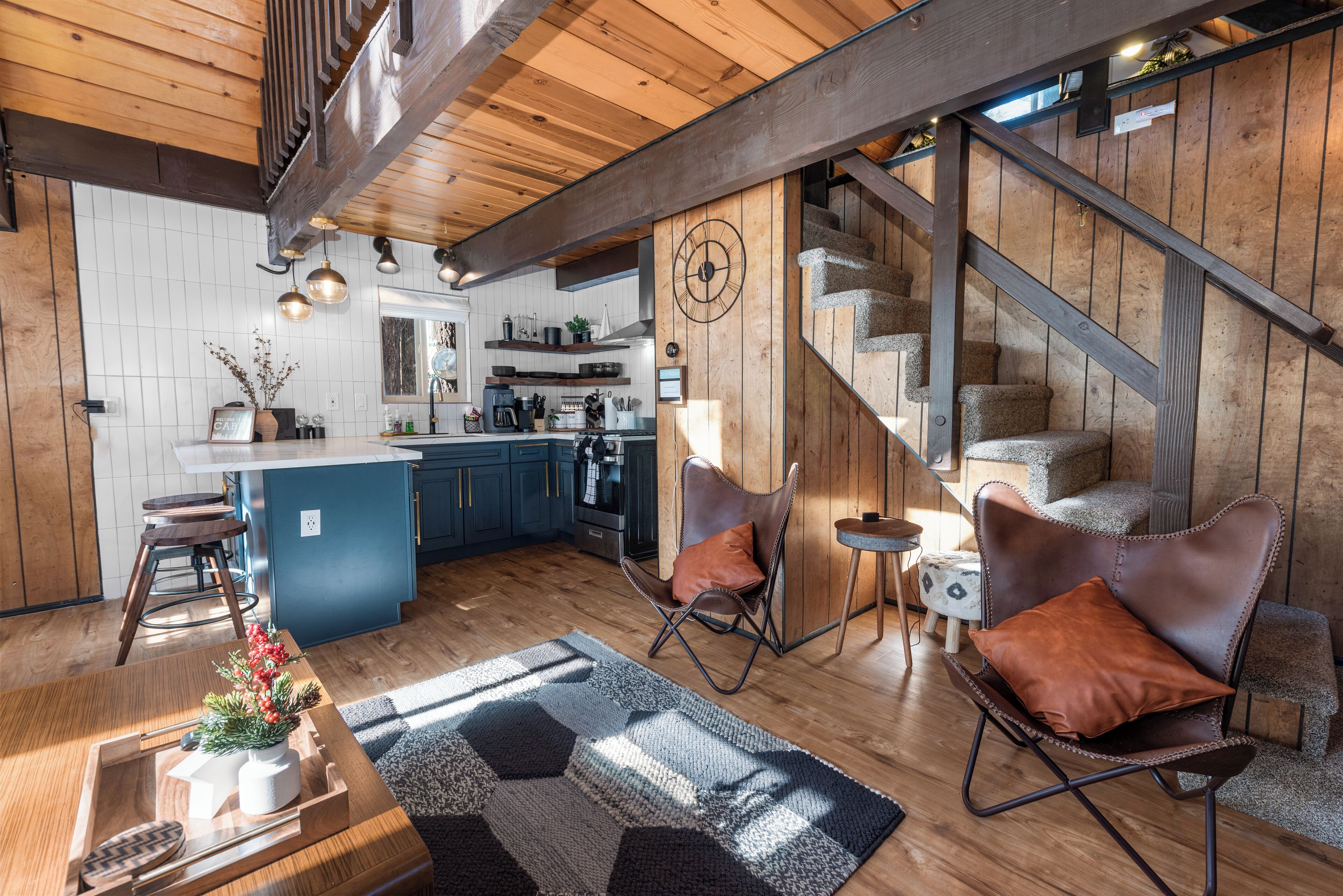 Una cocina moderna con armarios de madera, una isla central y una escalera que sube a un nivel superior.
