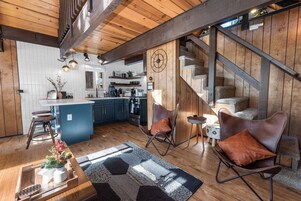 Una cocina moderna con armarios de madera, una isla central y una escalera que sube a un nivel superior.