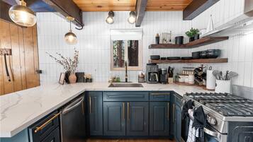 Una cocina moderna con armarios azul oscuro, una estufa de acero inoxidable y una encimera de mármol blanco.