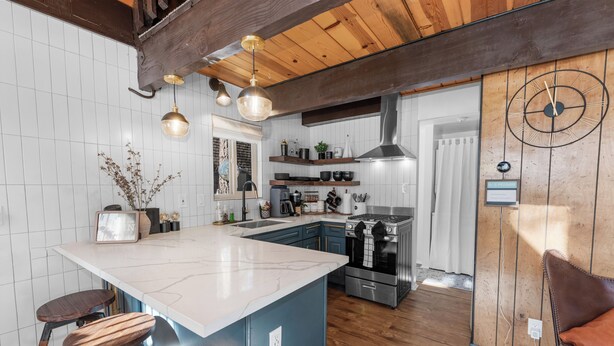 A modern kitchen with a large island, wooden ceiling beams, and stainless steel appliances. - Bearadise (Big Bear City)