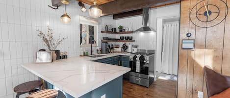 A modern kitchen with a large island, wooden ceiling beams, and stainless steel appliances.