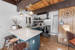 Una cocina moderna con una isla grande, vigas de madera en el techo y electrodomésticos de acero inoxidable.