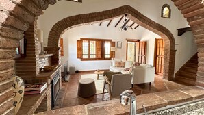 Un salón amplio con chimenea de piedra, un sofá blanco y una mesa de comedor.