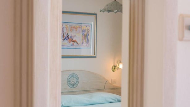 A bedroom with a bed, a wall-mounted light, and a framed picture. - Superb Le Residenze del Golfo di Orosei B4 -1 Bedroom Apartment Sleeps 4 Persons (Orosei)