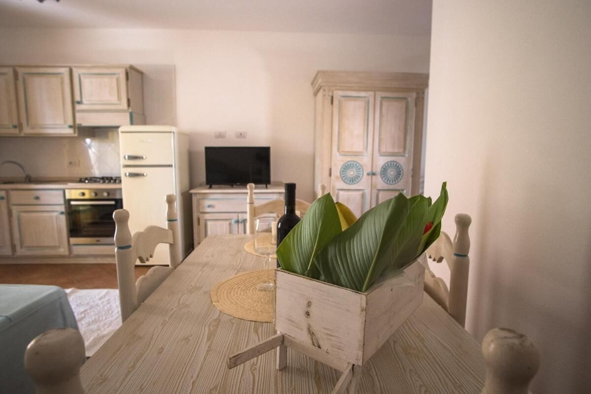 Een eettafel met stoelen, een televisie en een keuken op de achtergrond.