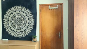 A room with a wooden door, a dark tapestry with a mandala design, and a small potted plant on a wooden dresser. - Cozy small ground floor house for 4, 600 m from beach and close to city center (Costa da Caparica)