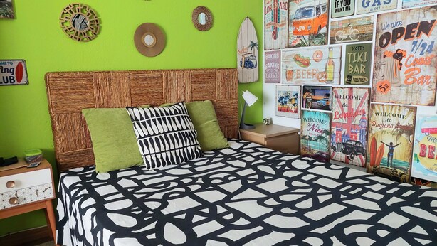A room with a bed, green walls, and various wall decorations including posters and a surfboard. - Cozy small ground floor house for 4, 600 m from beach and close to city center (Costa da Caparica)