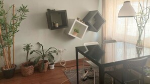 A room with a wooden floor, a glass table, and chairs, a black-framed mirror, and several potted plants. - Cozy small ground floor house for 4, 600 m from beach and close to city center (Costa da Caparica)