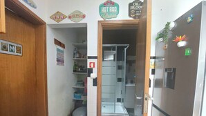 A compact kitchen with a refrigerator, a sink, and a small countertop. There are signs on the wall advertising gas and oil services. - Cozy small ground floor house for 4, 600 m from beach and close to city center (Costa da Caparica)