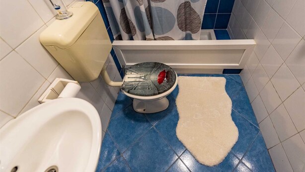 Een badkamer met toilet, bidet en een vloer van blauwe tegels.
