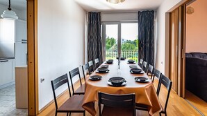 Een eetruimte met een lange tafel voor zes personen, zwarte stoelen en een moderne hanglamp.