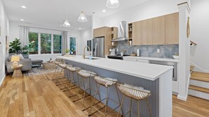 A modern kitchen with a central island, bar stools, and wooden cabinets.