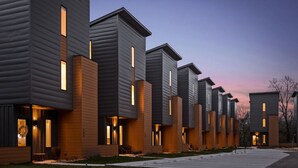 A row of modern, multi-story residential buildings with uniform design, featuring large windows and a mix of siding materials.