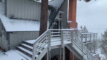 A wooden staircase leading to a building with a brick chimney and a metal door.