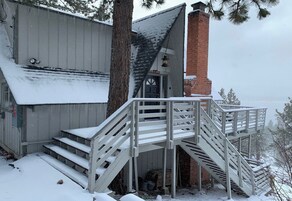 Una escalera de madera que conduce a un edificio con una chimenea de ladrillo y una puerta metálica.