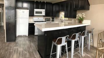 A modern kitchen with dark cabinets, a white island, and bar stools.