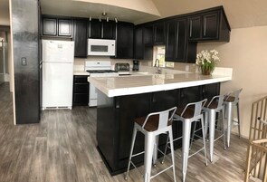Una cocina moderna con armarios oscuros, una isla blanca y taburetes de bar.