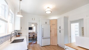 A modern kitchen with white cabinetry, a built-in stove, and a wooden countertop. - Newly Restored 2BR Heights Cottage (Little Rock)