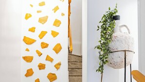 A hallway with a white wall, a wooden floor, a staircase, and a plant on a metal stand. - Napoleon Olive Home 2bd 1ba (Hersonissos)