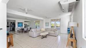 A spacious living room with a large sofa, a coffee table, and a dining area with chairs. - Dos Culebras House-Private Pool (Puntas)