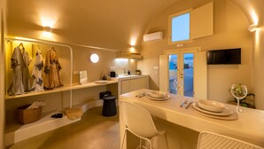 A compact, well-lit kitchen with a dining area, featuring a built-in oven, a sink, and a small window.