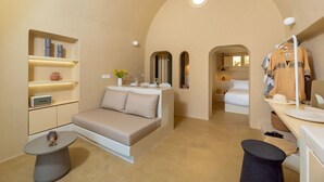 A modern, compact room with a sofa, a small table, a mirror, and a bed.
