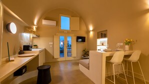 A modern kitchen with a built-in oven, a dining area with two white chairs, and a large window with a view of the outdoors.