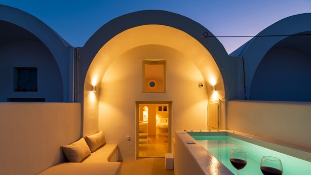 A modern hotel room with a bathtub, two wine glasses, and a cozy seating area.