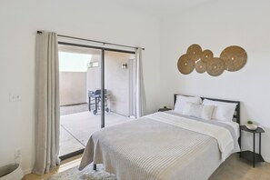 Ein Schlafzimmer mit einem Bett, einem Nachttisch, einem Wanddekor und einer Glastür zum Balkon.