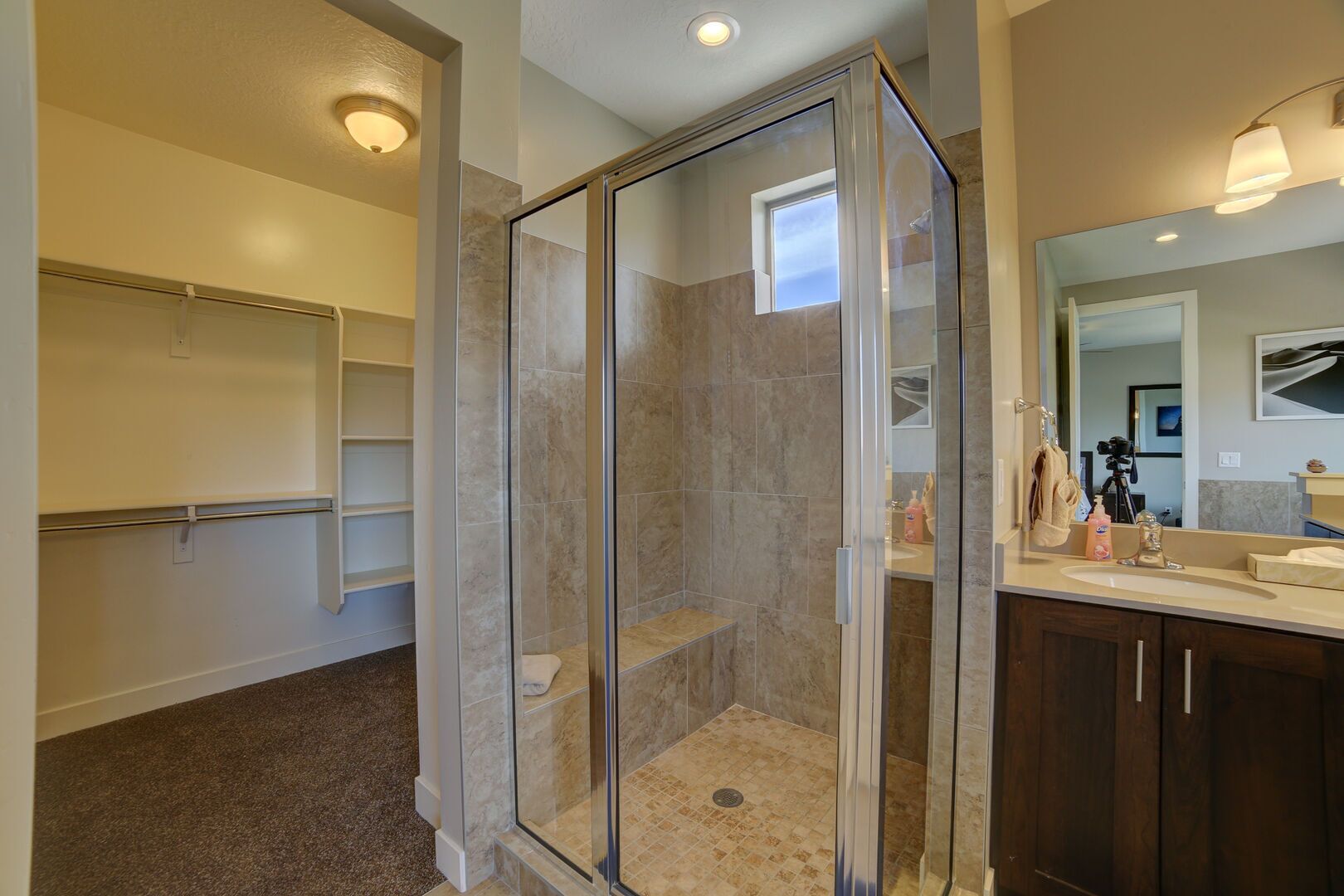 A modern bathroom with a glass-enclosed shower, a vanity with a mirror, and built-in shelving.