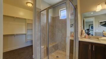 A modern bathroom with a glass-enclosed shower, a vanity with a mirror, and built-in shelving.