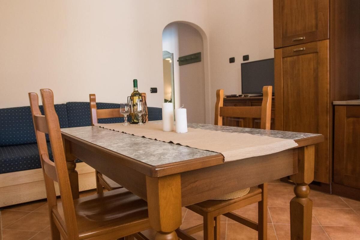 A dining area with a wooden table, chairs, a candle, and a bottle of wine.