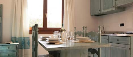 A dining area with a table set for four, a window with curtains, and light blue cabinets.