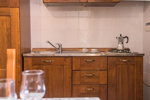 A kitchen with wooden cabinets, a stainless steel sink, and a coffee maker.