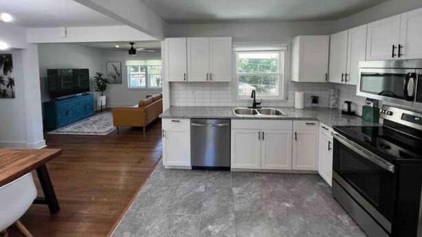 A modern kitchen with white cabinets, a stainless steel sink, a built-in oven, and a microwave. - Atlanta Home - 10 min from everything! (Atlanta)