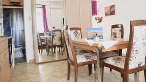 A dining area with a wooden table, floral chairs, and a view of the bathroom through a sliding door.