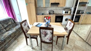 A compact living space with a dining table, chairs, a sofa, and a kitchenette.