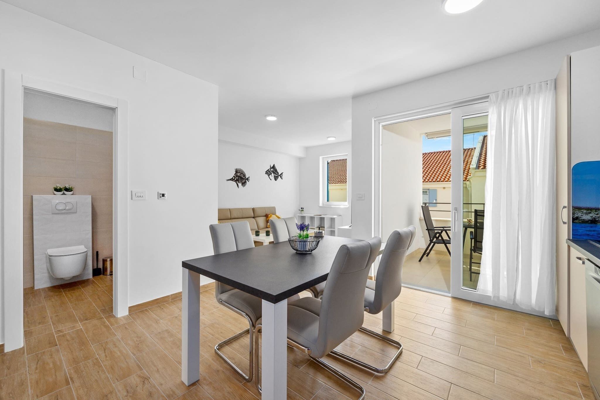 A modern kitchen with a dining area, a sliding glass door to the outside, and a view of the neighborhood.