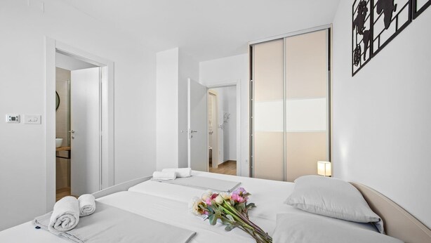 A hotel room with a bed, a bedside table, a lamp, and a mirror. - Apartment Tim (Cres)