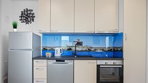 A modern kitchen with a built-in dishwasher, oven, and a backsplash with a coastal scene. - Apartment Tim (Cres)