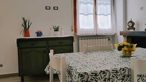 A dining area with a table set for four, a window with curtains, a radiator, and a clock on the wall. - Rickymary House, Pet Friendly (Senigallia)