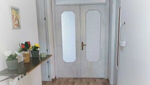 A hallway with a wooden floor, a white radiator, a door with frosted glass panels, and a small table with potted plants. - Rickymary House, Pet Friendly (Senigallia)