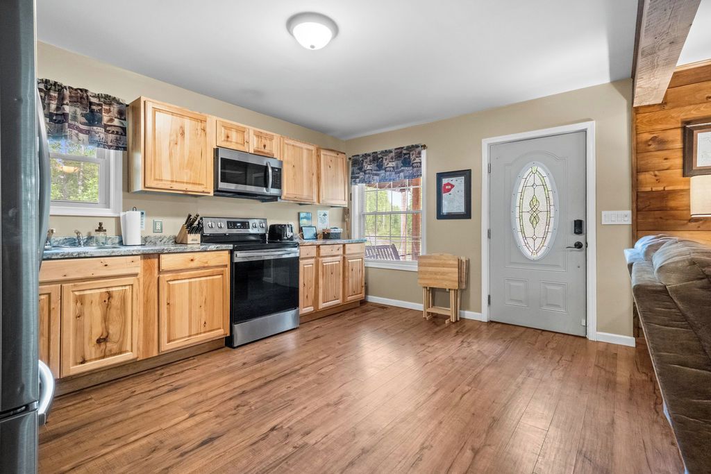 A kitchen with wooden cabinets, stainless steel appliances, and a door with a decorative glass window.