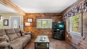 Ein gemütliches Wohnzimmer mit einer Couch, einem Couchtisch, einem Fernseher und Holzwänden.